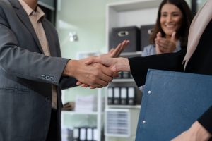 happy businessman and businesswoman shaking hands at group board